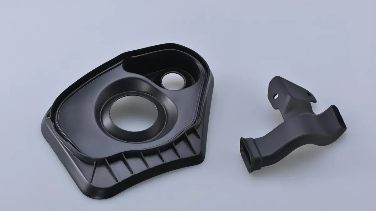 Black injection-moulded plastic parts on a light surface