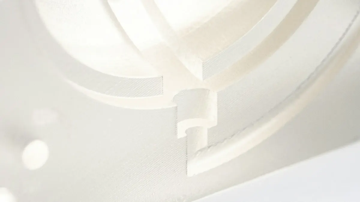 Close-up of a white 3D-printed part showing walls and curved channels